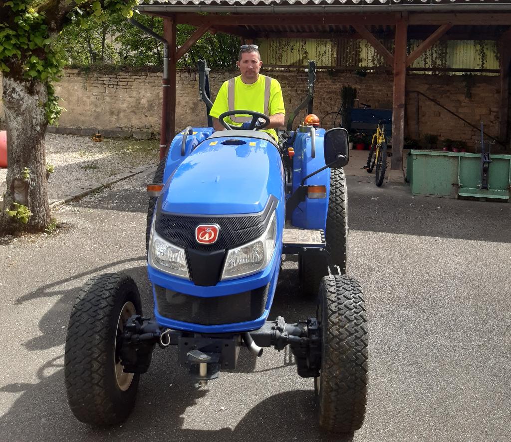 Dave Millot nouvel employé municipal assis sur un tracteur bleu.